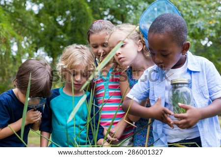 Happy siblings looking at a jar on a sunny day