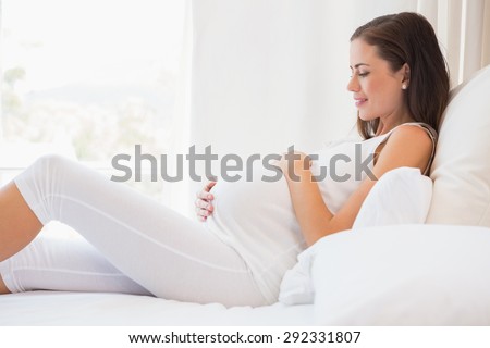 Happy pregnancy sitting on sofa at home in bedroom