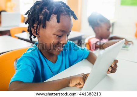 Side view of pupil using tablet pc in classroom at elementary school