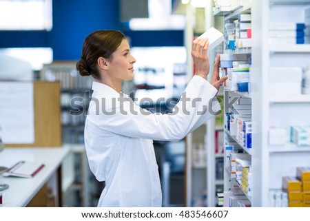 Pharmacist checking medicine in shelf at pharmacy