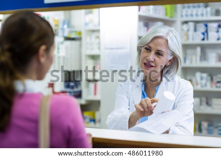Pharmacist assisting the bottle of drug to customer in pharmacy