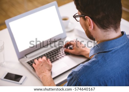 Rear view of young male executive typing on laptop at creative office
