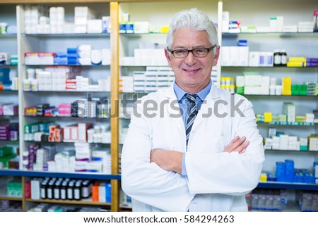 Portrait of pharmacist standing with arms crossed in pharmacy