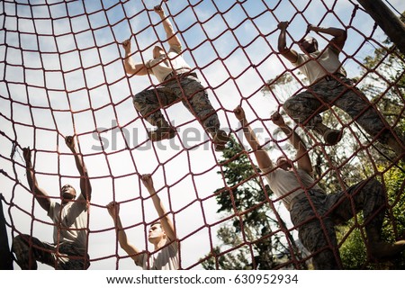 Military soldiers climbing rope during obstacle course in boot camp