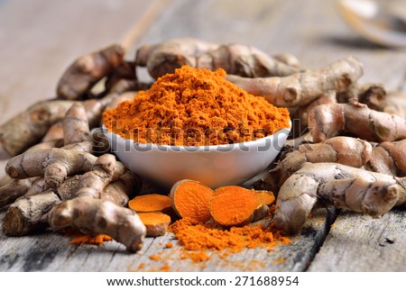 turmeric powder in white dish on wooden background