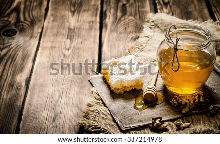 Honey background. Sweet honey in the comb, glass jar with nuts. On wooden background.