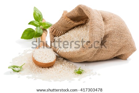 Raw grain white rice grains in burlap bag decorated with green basil isolated on white background.