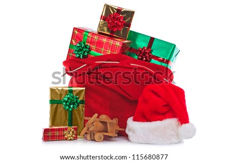 Photo of a red Santa Claus hat and sack full of gift wrapped presents and toys, isolated on a white background.