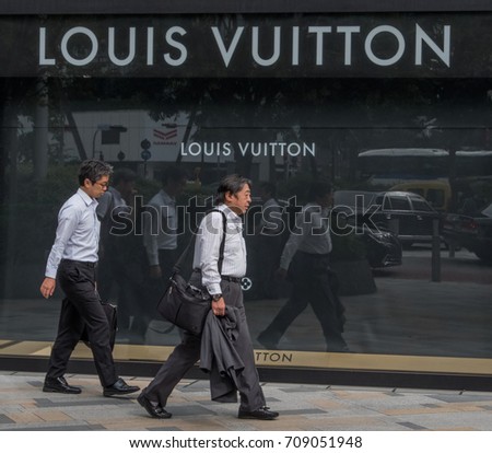 TOKYO, JAPAN - SEPTEMBER 1ST, 2017. Japanese white collar workers or salaryman walking in front of Louis Vuitton outlet at Tokyo station.