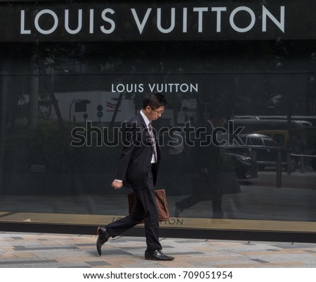 TOKYO, JAPAN - SEPTEMBER 1ST, 2017. Japanese white collar workers or salaryman walking in front of Louis Vuitton outlet at Tokyo station.