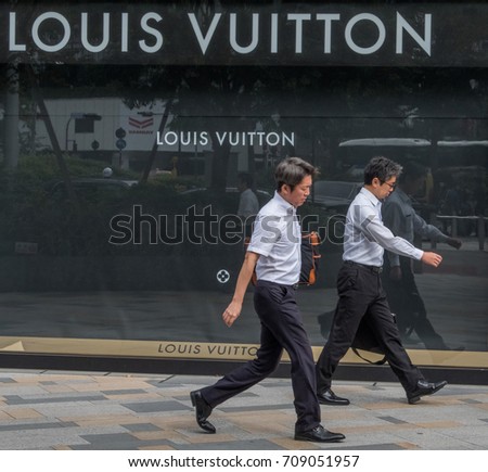 TOKYO, JAPAN - SEPTEMBER 1ST, 2017. Japanese white collar workers or salaryman walking in front of Louis Vuitton outlet at Tokyo station.