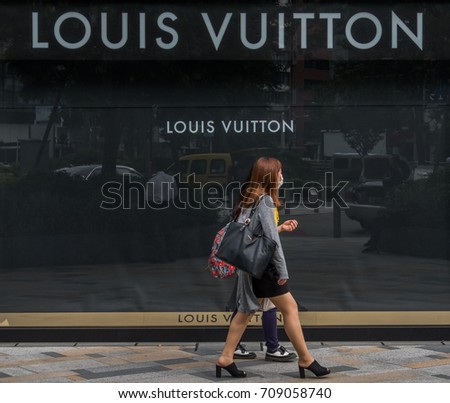 TOKYO, JAPAN - SEPTEMBER 1ST, 2017. Woman walking in front of Louis Vuitton outlet at Tokyo Station.