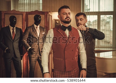 Tailor measuring client for custom made suit tailoring