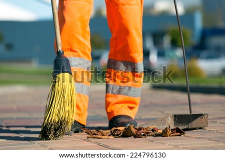 City street male or female sweeper cleaning pavement with broom tool