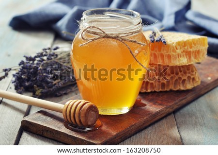 Honey in jar with honey dipper on vintage wooden background