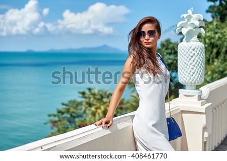 Beautiful brunette young woman wearing white dress and sunglasses