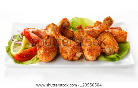 Grilled chicken drumsticks and vegetables on white background - stock photo
