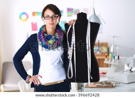 Smiling fashion designer standing near mannequin in office