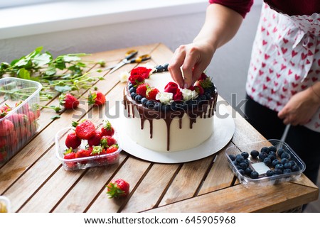 Baker adding blueberries to a cake