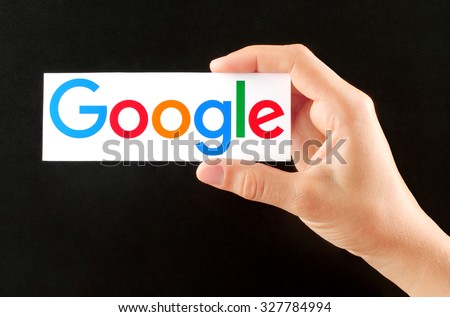 Kiev, Ukraine - September 02, 2015:Hand holds new Google logotype printed on paper on blackboard background.Google is USA multinational corporation.