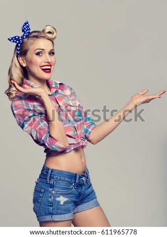 stock photo young smiling woman dressed in pin up style showing something or copyspace area for text or slogan 611965778