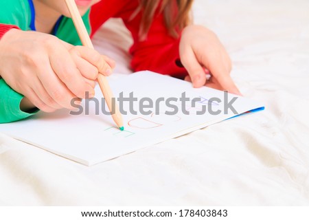 hands of mother and child writing letters, early education
