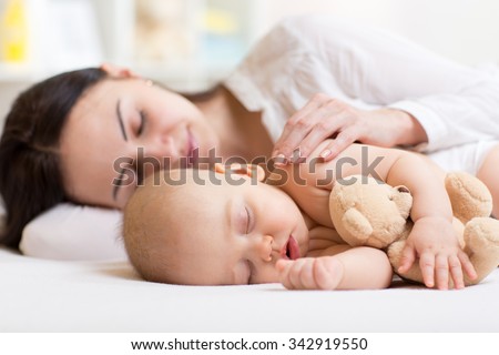 beautiful woman and her son little baby sleeping together in a bedroom