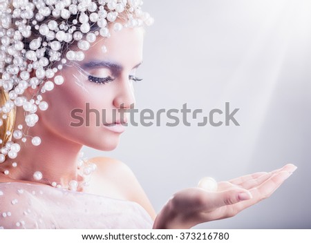 Portrait of beautiful woman with fantasy make-up with hair of white pearls on a light background