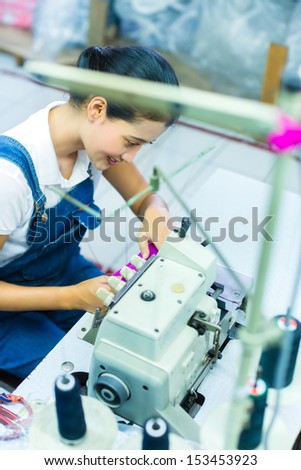 Asian Seamstress or worker in a Indonesian factory sewing with a industrial sewing machine, she is very accurate