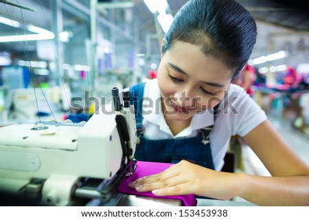 Asian Seamstress or worker in a Indonesian factory sewing with a industrial sewing machine, she is very accurate