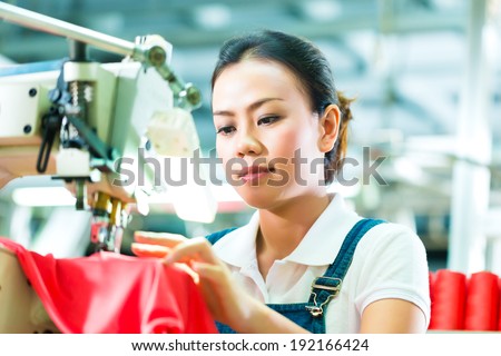Seamstress or worker in a chinese factory sewing with a industrial sewing machine, she is very accurate