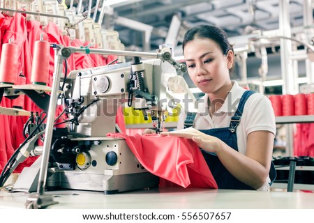 Seamstress or worker in Asian textile factory sewing with industrial sewing machine