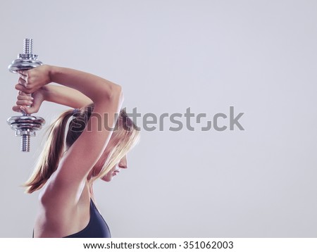 Bodybuilding. Strong fit woman exercising with dumbbell. Muscular blonde girl lifting weights