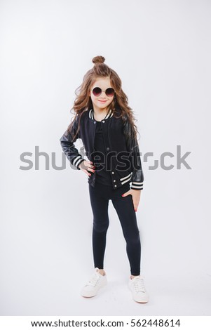 Portrait of little hipster girl in sunglasses. Posing. Curly modern hairstyle