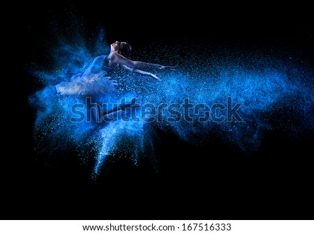 Young beautiful dancer jumping into blue powder cloud