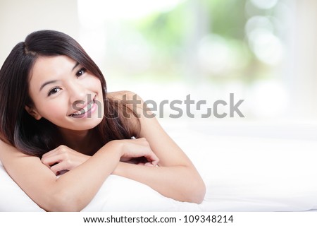 Charming woman Smile face close up and she lying on the bed in the morning with nature green background, model is a asian girl