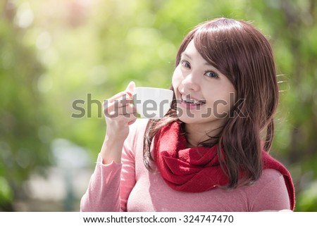 smile young woman holding cup of coffee or tea and wearing winter clothing with green background, asian beauty