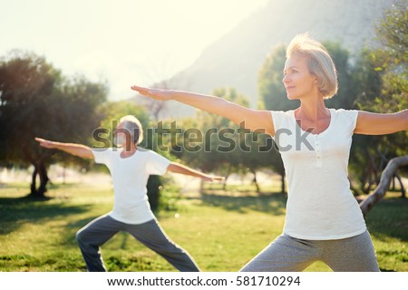Yoga at park. Senior family couple exercising outdoors. Concept of healthy lifestyle.