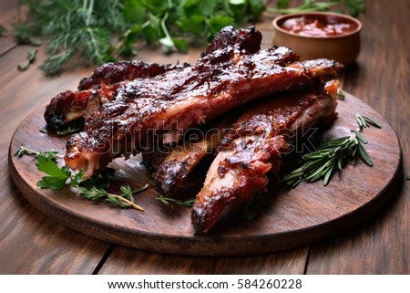 Grilled sliced barbecue pork ribs on wooden board, shallow depth of field