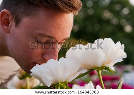 https://thumb1.shutterstock.com/display_pic_with_logo/871384/164845988/stock-photo-man-smells-flowers-in-the-field-at-sunset-164845988.jpg