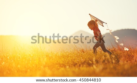 happy child girl with a kite running on meadow in summer in nature