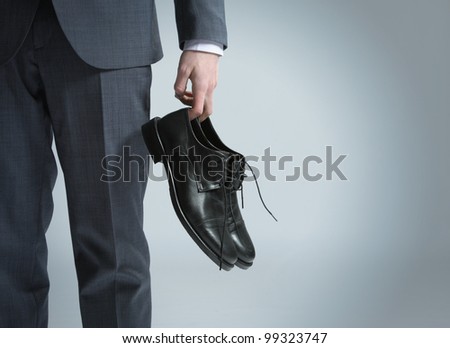 businessman holding the shoes in hand, close up