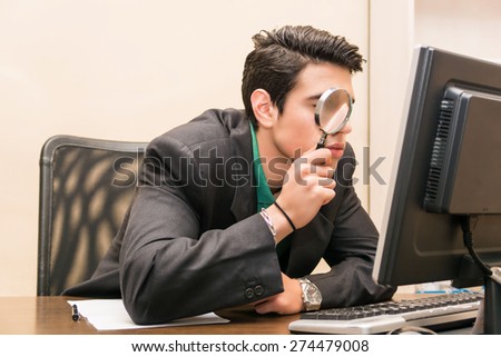 stock-photo-young-businessman-sitting-at-his-desk-searching-through-magnifying-glass-in-front-of-computer-274479008.jpg