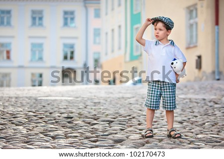 Cute little boy sitting on father's shoulders outdoors in city park