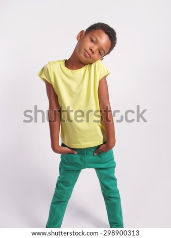 A boy standing with hands in the pockets over grey background. Vertical Shot.