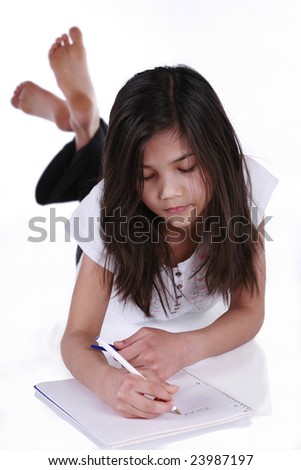 Child writing in notebook while lying on floor