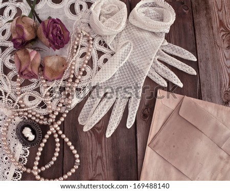 Vintage women's jewelry and gloves. Retro concept with dried roses on a wooden background