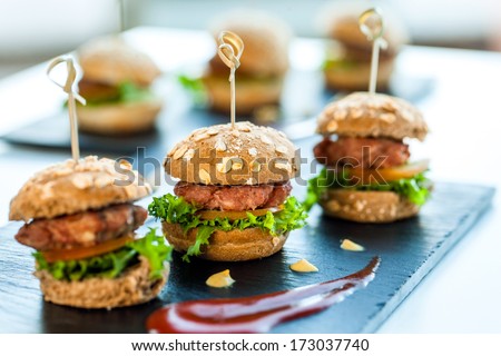 Close up of mini hamburgers at catering event. - stock photo