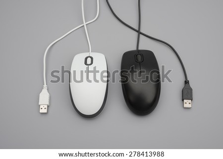 white and black mouses with cables twisted on grey background