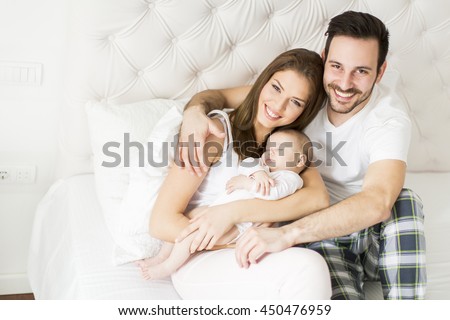 Happy family with newborn baby on the bed in the room Happy family with newborn baby on the bed in the room